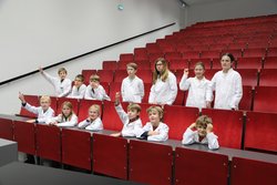 Gruppe von Kindern in weißen Labormänteln in einem Hörsaal der Montanuniversität